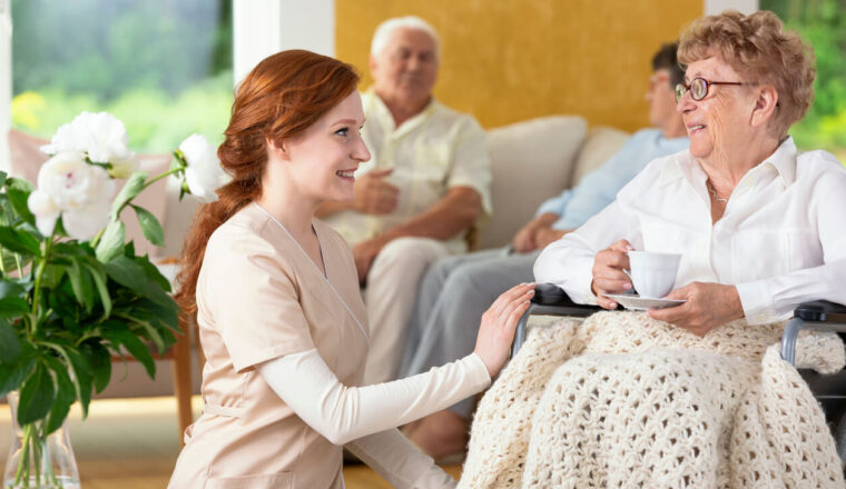 Smiling nurse taking care of disabled senior woman