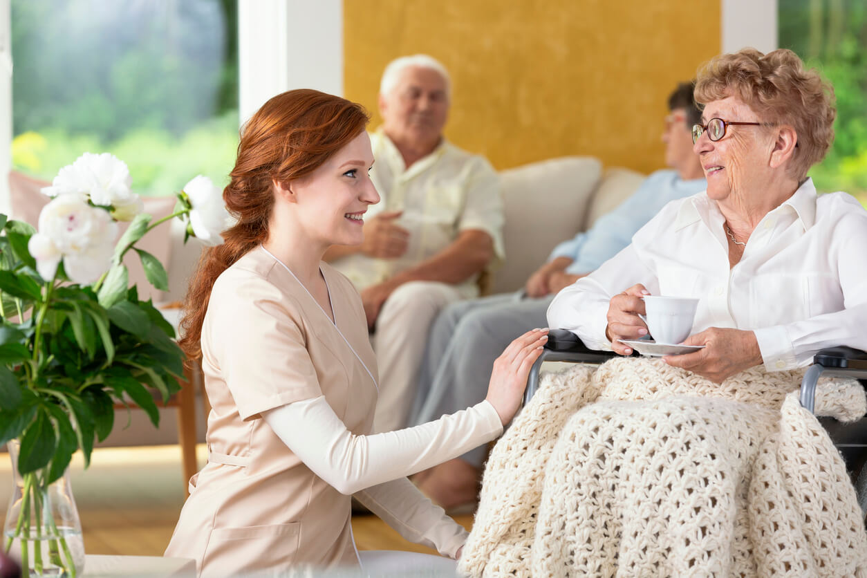 Smiling nurse taking care of disabled senior woman