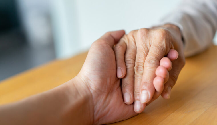 close up senior woman hand touching health worker man hand