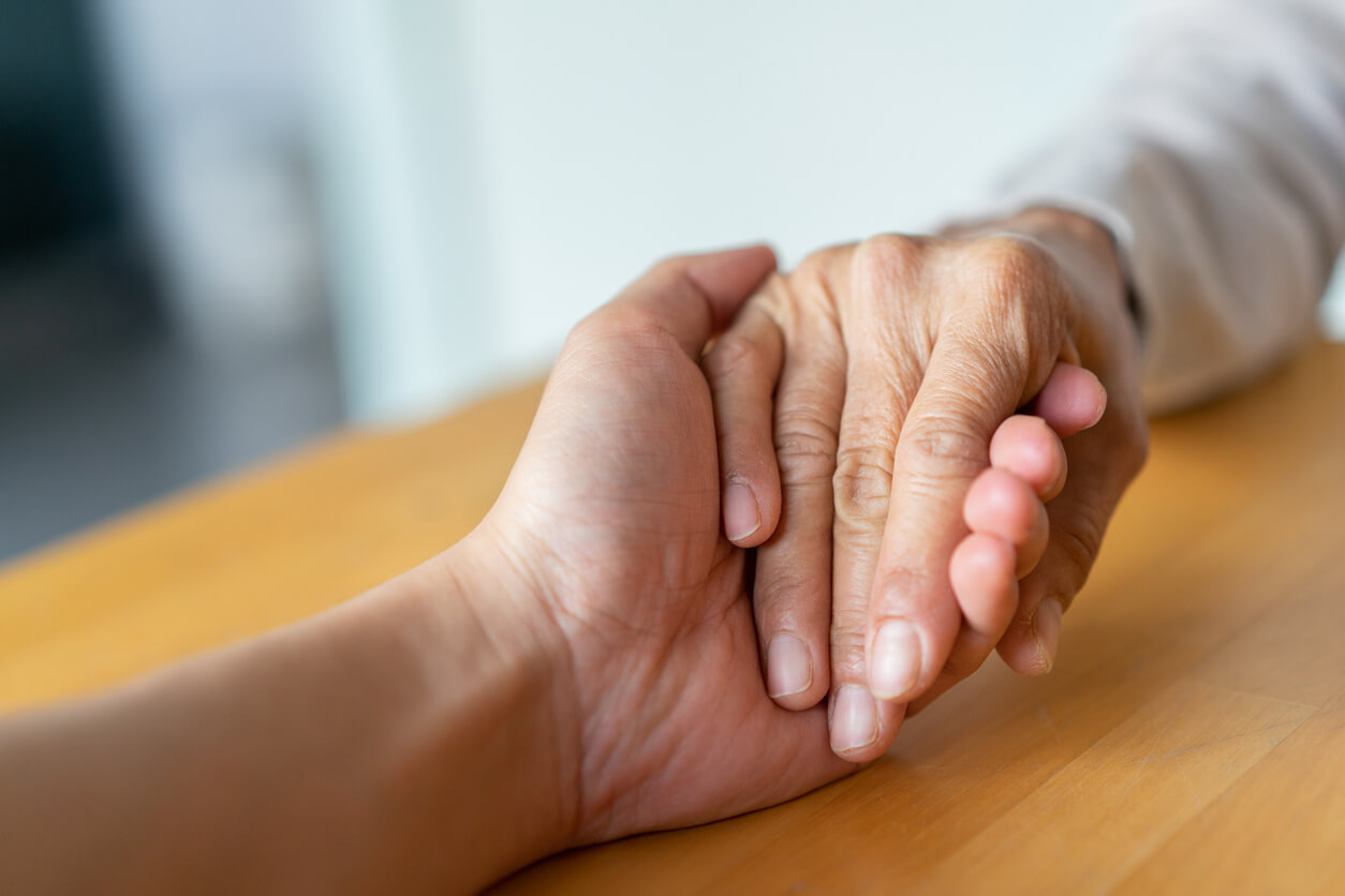 close up senior woman hand touching health worker man hand